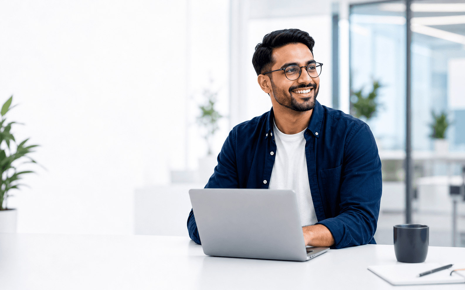 A smiling professional using a laptop in a bright office.